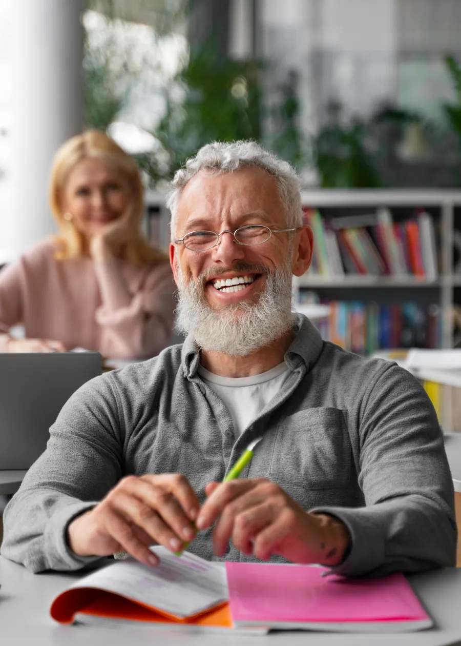 Homem sorrindo durante um estudo em grupo, com anotações sobre a mesa